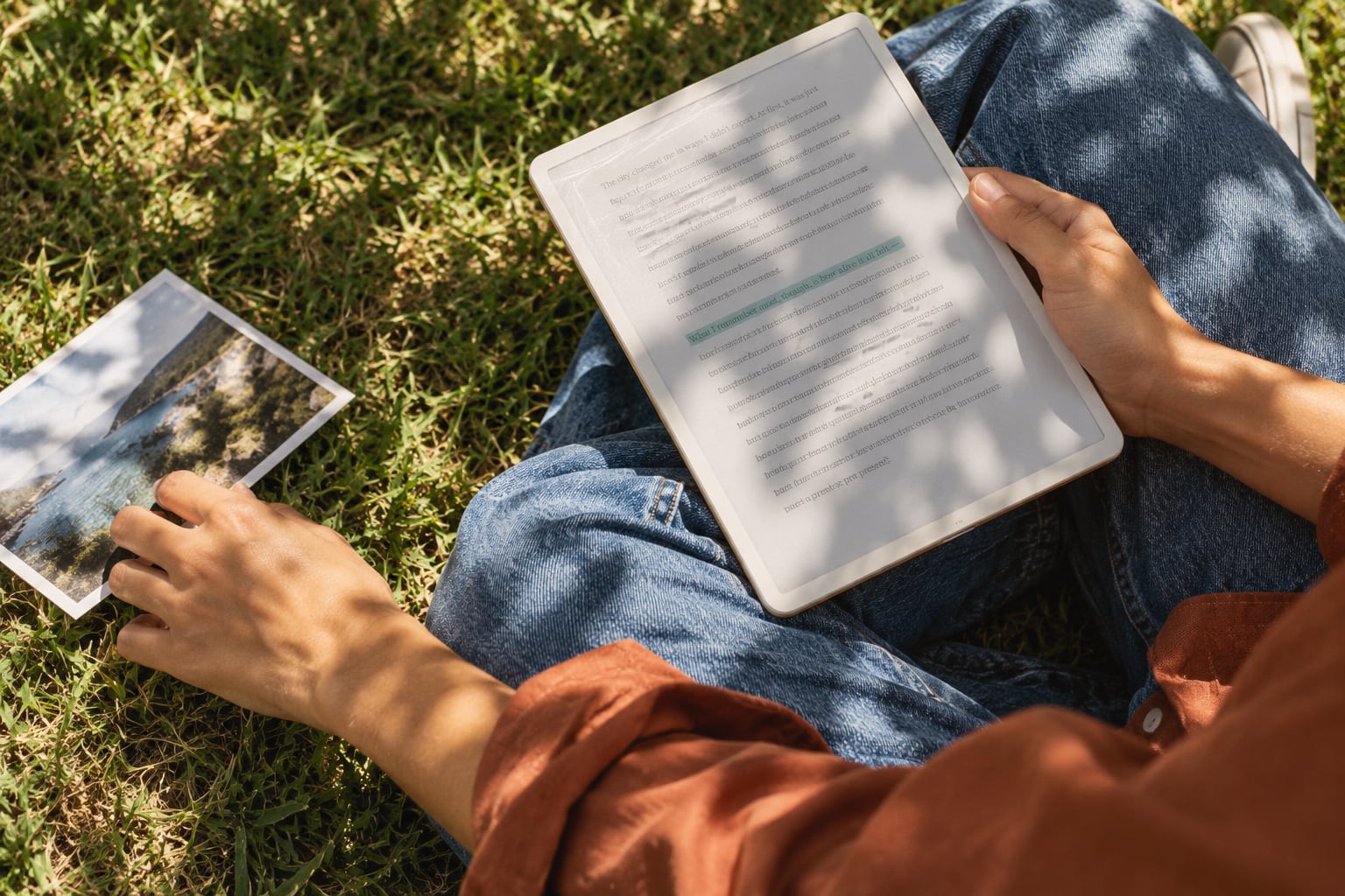 Reading on a tablet in the grass, a printed photograph beside it